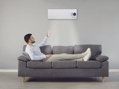 Mann på sofa bruker fjernkontroll til veggmontert varmevifte i moderne stue